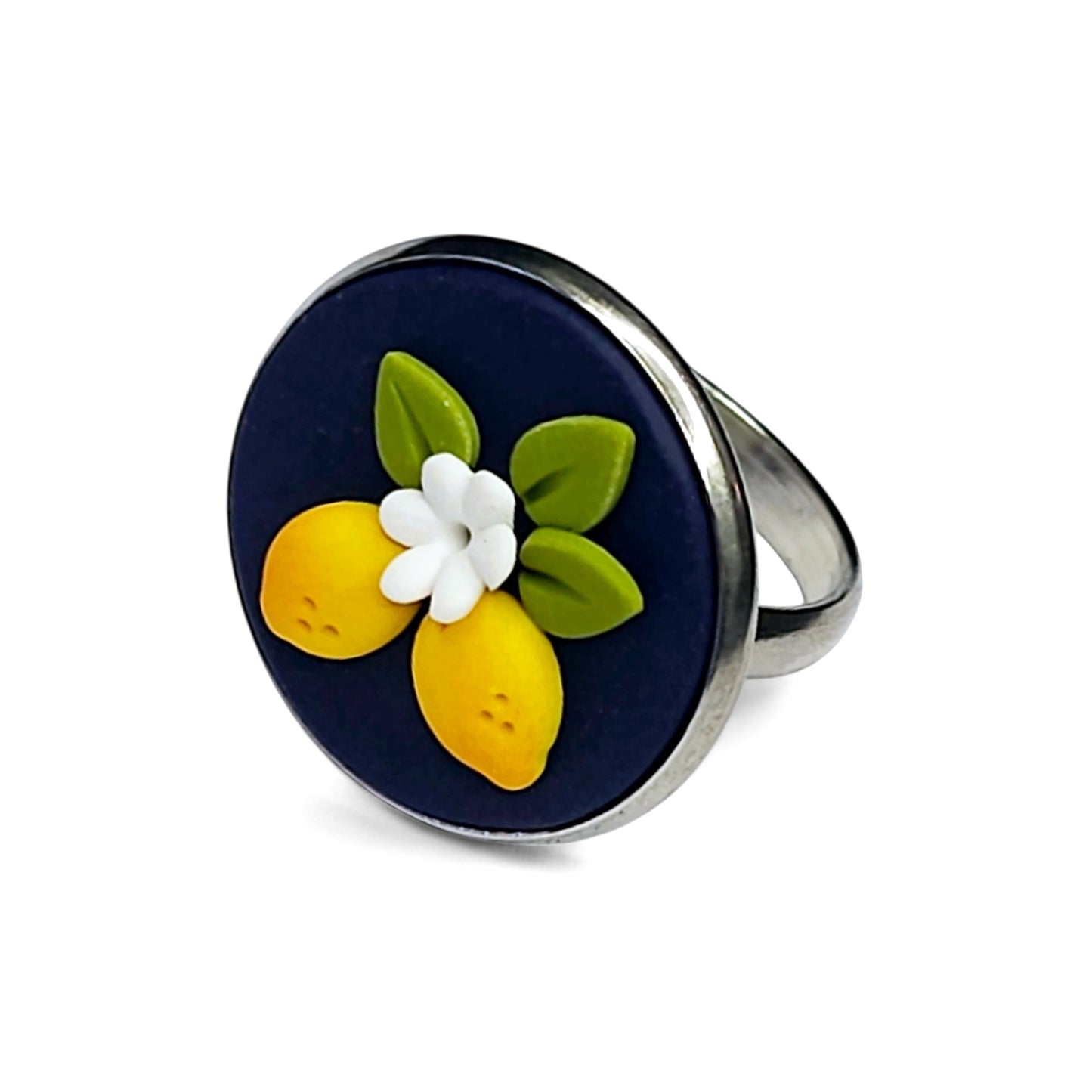 Στρογγυλό ατσάλινο δαχτυλίδι με κίτρινα λεμόνια σε μπλε φόντο από πολυμερικό πηλό